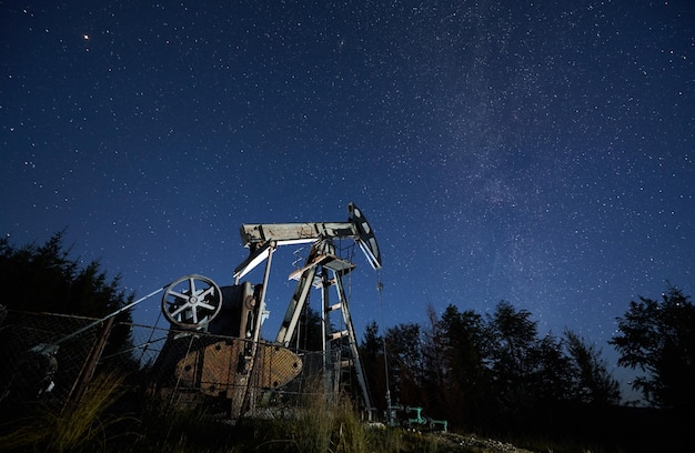 Campo petrolero con toma de bomba de petróleo bajo el cielo estrellado de la noche