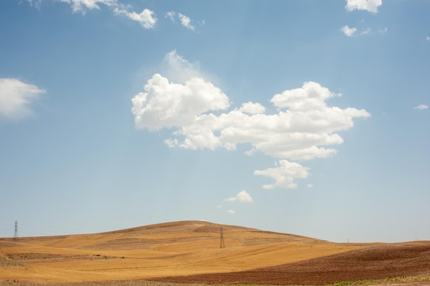 Foto campo de trigo cosechado en la colina con cielo azul y parcialmente nublado en la provincia de kurdistán, irán