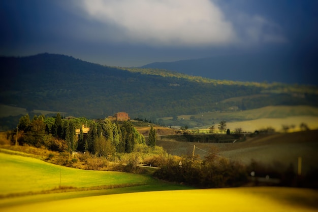 Campos ondulados na Toscana com sombras e fazendas Itália Fundo de primavera sazonal ao ar livre natural com céu dramático azul e nuvens