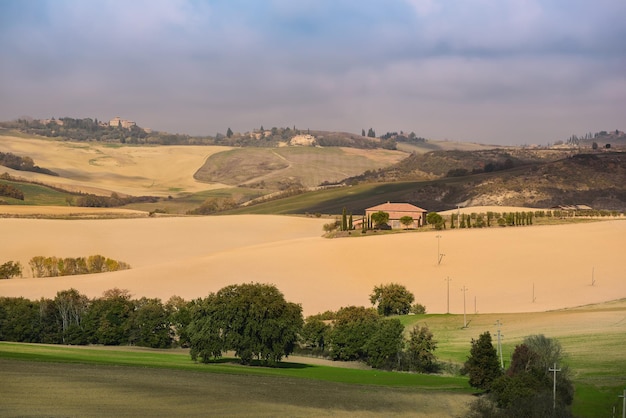 Campos ondulados na toscana com sombras e fazendas itália fundo de verão sazonal ao ar livre natural com céu azul e nuvens