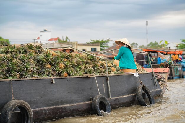Can Tho, Vietnam - 28. Februar 2016: Frauen in einem Boot, das Ananas auf dem sich hin- und herbewegenden Markt am Delta Mekong in Can Tho, in Vietnam verkauft