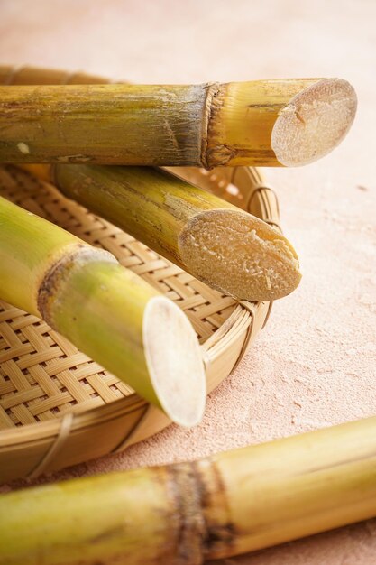 Caña de azúcar y hoja verde en una bandeja de madera sobre un fondo beige Primer plano