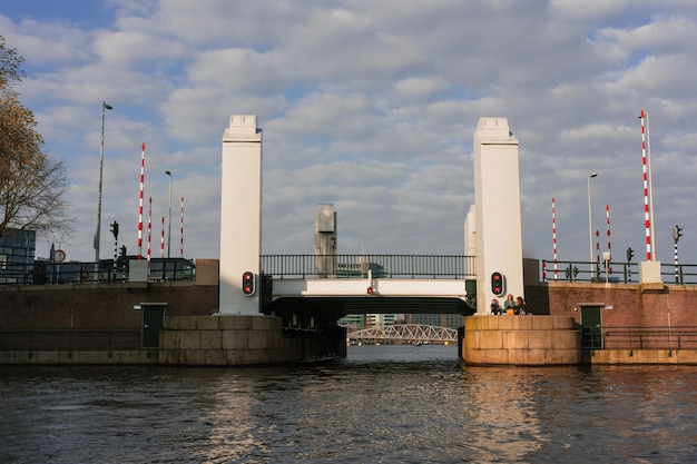 Canais estéticos de Amsterdã ao pôr do sol vista da água da ponte levadiça moderna do rio Passeio de barco romântico em Amsterdã