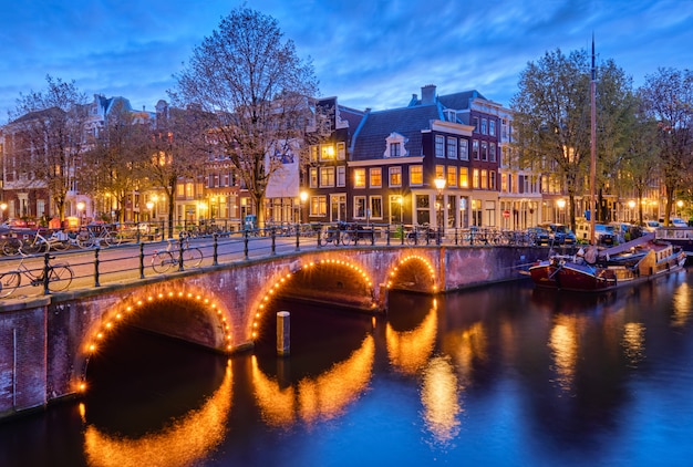 Canal de amterdam, puente y casas medievales en la noche