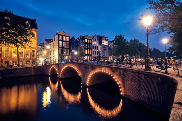 Canal de amterdam, puente y casas medievales en la noche