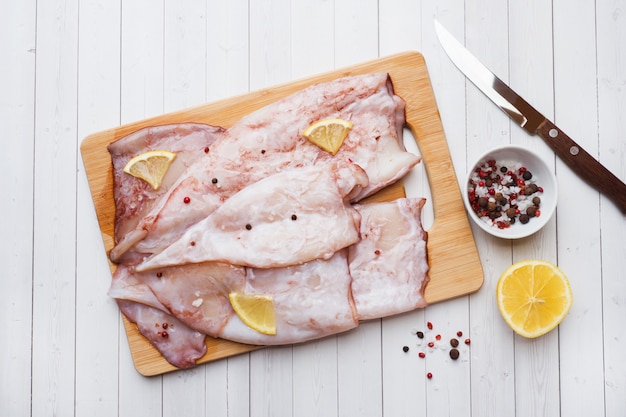 Canal de calamar crudo con especias y limón listo para cocinar en la mesa.