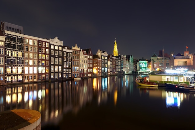 Canal de Amsterdã com casas típicas e a igreja Oude Kerk durante o crepúsculo, Holanda, Holanda