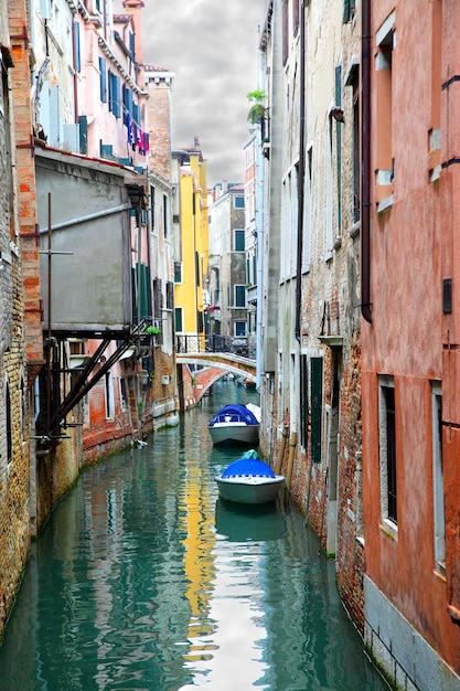 Canal estrecho con barcos en Venecia, Italia