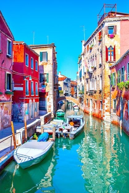 Canal lateral estrecho con lanchas amarradas en Venecia en un día soleado, Italia