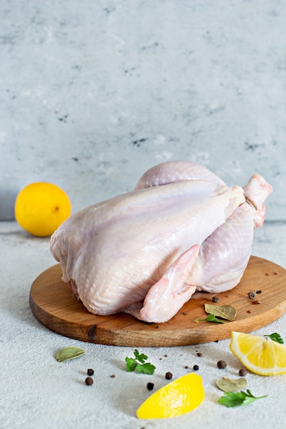 Canal de pollo crudo listo para cocinar sobre una tabla de cortar sobre un fondo gris