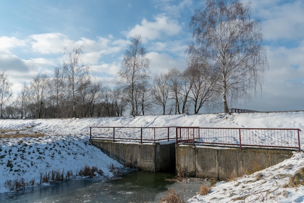 Canal de riego a lo largo de un campo agrícola en invierno cubierto de nieve y hielo Paisaje invernal agrocomplejo ecológico Plantas de tratamiento de aguas residuales