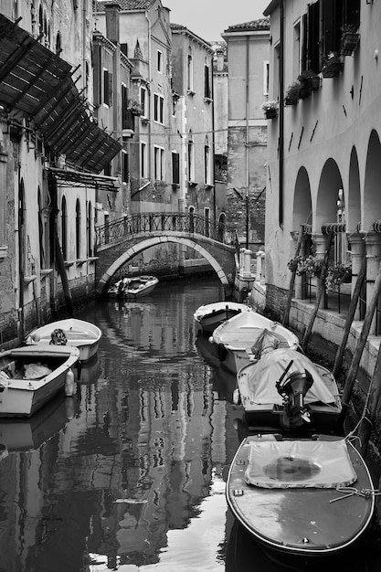 Canal de Venecia con barcos amarrados, Italia. Fotografía en blanco y negro, vista veneciana