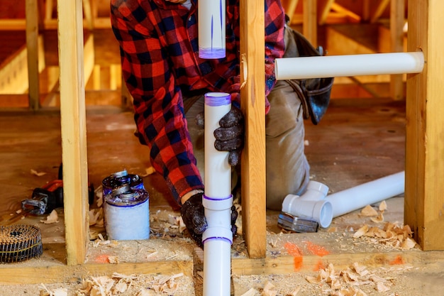 Foto canalizador cola tubo de pvc branco, um novo dreno de plástico de montagem na nova casa