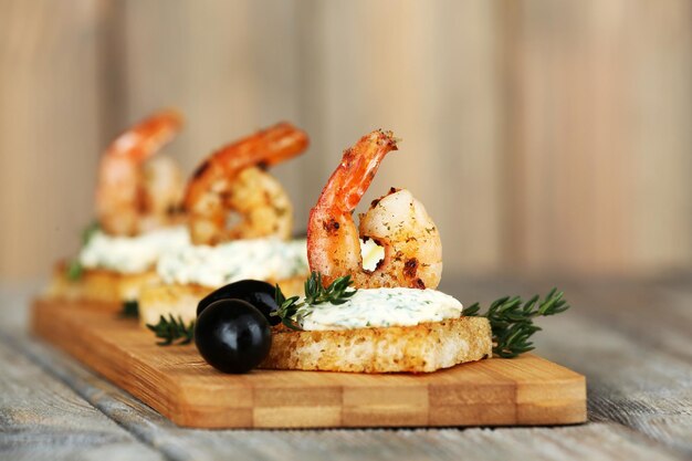 Canapé de aperitivo con camarones y aceitunas sobre fondo de madera