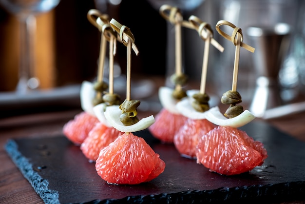 Canapé, aperitivo. Pomelo, alcaparras y cebollas en un pincho. Fiesta de comida.