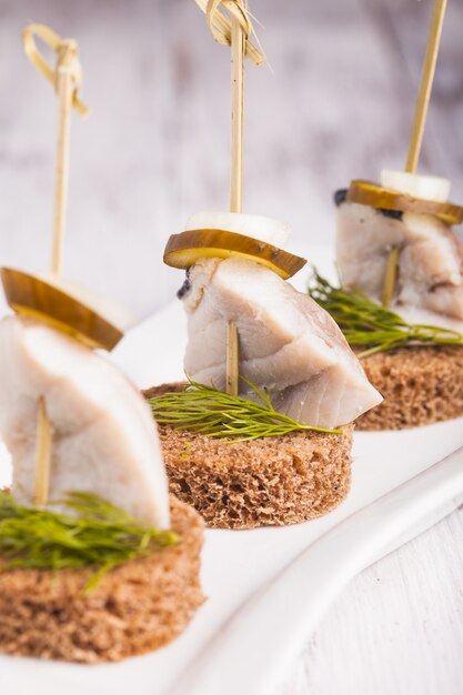 Canapé de arenque con cebolla, pepino encurtido y eneldo