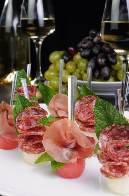 Canape aus Wassermelonenbällchen mit einer Melone mit Schinken und Salami