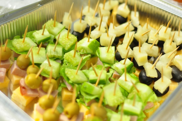 Canapé en brochetas con lechuga y toppings queso y jamón aceitunas y pepinos