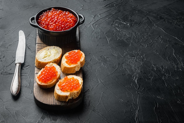 Canapé con caviar de salmón rojo para año nuevo, sobre fondo negro con espacio para copiar texto