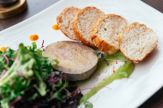 Canape mit Gänseleberpastete und Salat serviert mit Weißwein.