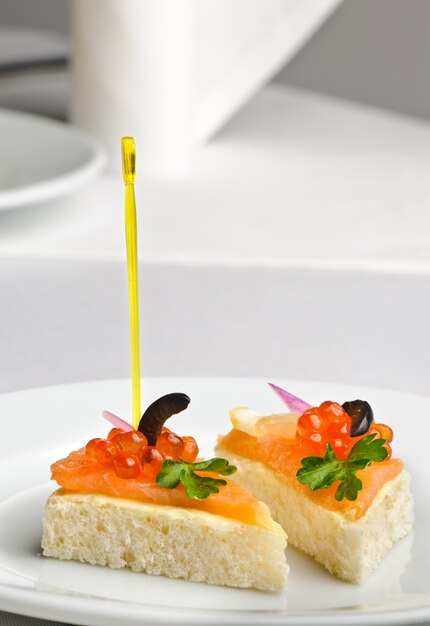 Canape mit rotem Kaviar und geräuchertem Lachs, serviert auf Teller
