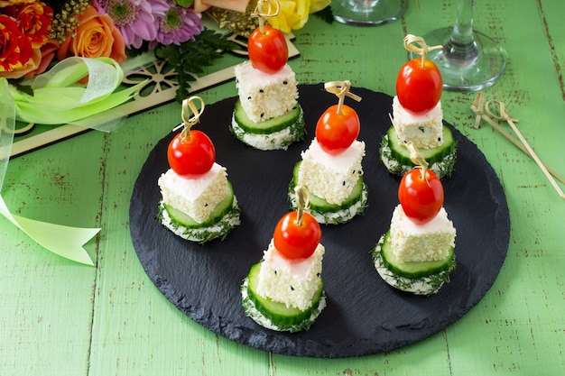 Canapé con pan blanco, pepino, queso feta y tomates cherry en una mesa festiva. San Valentín o boda.