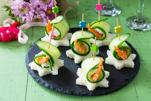 Canapé con pan blanco, pepino, ricotta y gambas reales en una mesa festiva. Concepto de San Valentín o boda.