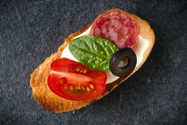 Canapé de sándwich de cara abierta o crostini sobre fondo de piedra oscura primer plano Vista superior