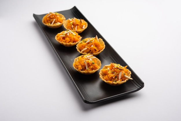 Canapé de zanahoria o Gajar Halwa o canapé o Tarta de fusión, aderezado con frutos secos. Postre indio