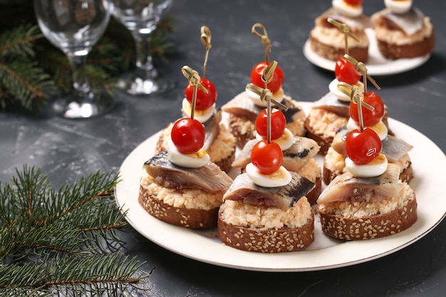 Canapés com arenque salgado, queijo, ovos de codorna e tomate cereja em pão de centeio