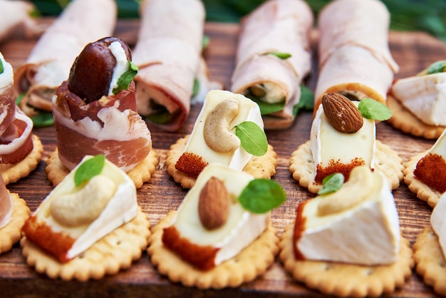 Canapés diferentes com salmão defumado, pepino, tomate, queijo, carne. mesa de buffet de café da manhã com uma variedade de lanches. buffet servido mesa com lanches, frutas, canapés, doces e aperitivos.