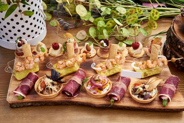 Canapés diferentes com salmão defumado, pepino, tomate, queijo, carne. mesa de buffet de café da manhã com uma variedade de lanches. buffet servido mesa com lanches, frutas, canapés, doces e aperitivos.