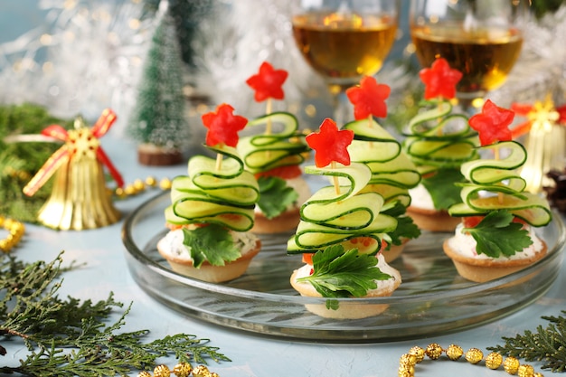 Canapés festivos em forma de árvores de Natal feitos de pepinos e estrelas de pimentão em azul claro