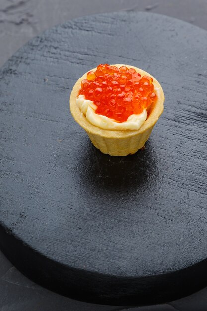 Canapés con mantequilla y caviar rojo sobre una placa redonda negra