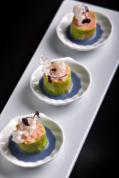 Foto canapés de salmón al horno con salsa, en pequeños platillos blancos, comida de catering de concepto.