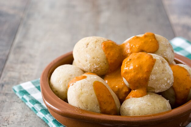 Canárias batatas com molho mojo na mesa de madeira.