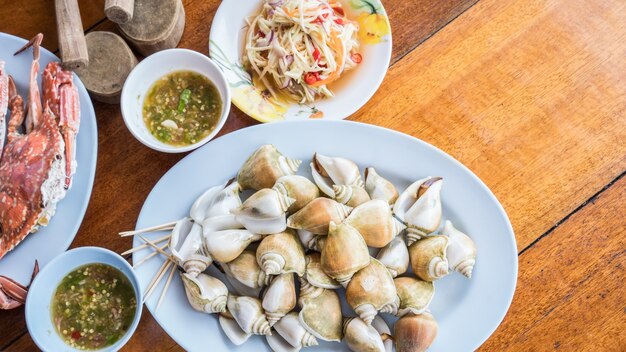 Foto canarium laevistrombus fresco cozido ou caracol marinho com salada de manga crua e frutos do mar picante sa