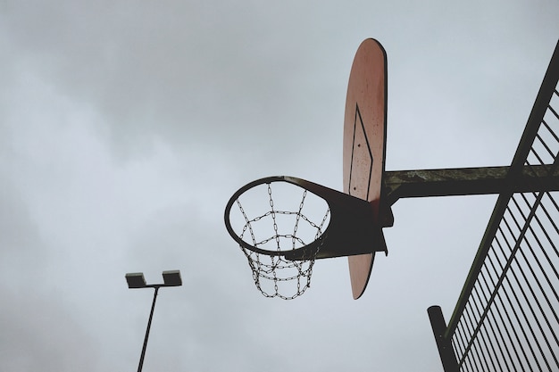 Canasta de baloncesto deportiva con red metálica en la calle.