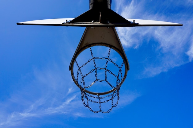 canasta de baloncesto con red metálica y cielo azul en la calle