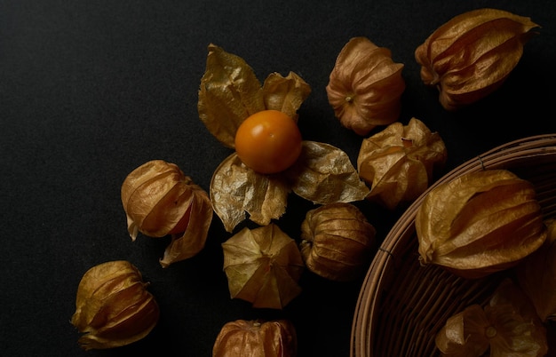 Una canasta de bayas de goji secas se sienta sobre una mesa negra.