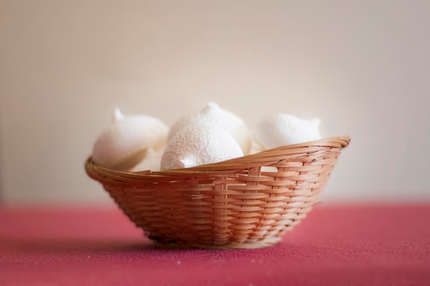 Una canasta de besos de merengue blanco sobre un fondo rojo.