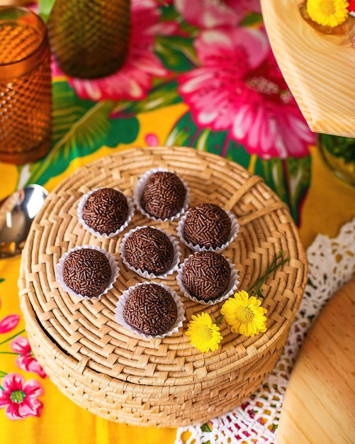 Una canasta de bolas de chocolate con una flor en el mantel.