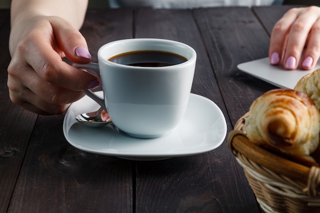 Canasta con deliciosos cruasanes recién hechos y una taza de café caliente por la mañana