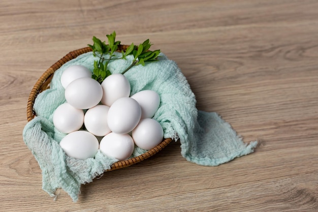 Una canasta de huevos con hojas verdes sobre una mesa de madera