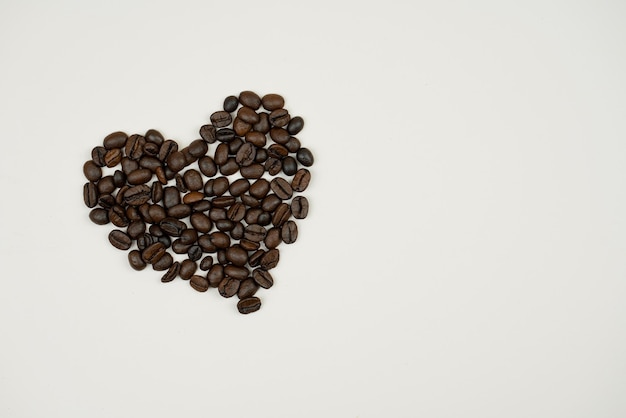 Una canasta de madera vertió granos de café juntos en forma de corazón en una hermosa tabla de madera