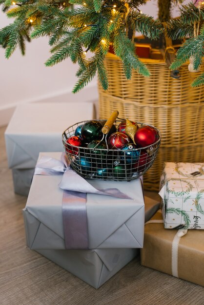 Foto canasta de metal con juguetes de navidad, cajas de regalo y regalos debajo del árbol de navidad.