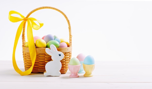 Foto una canasta de mimbre llena de coloridos huevos y flores para las vacaciones de pascua huevos coloridos en puestos de huevos