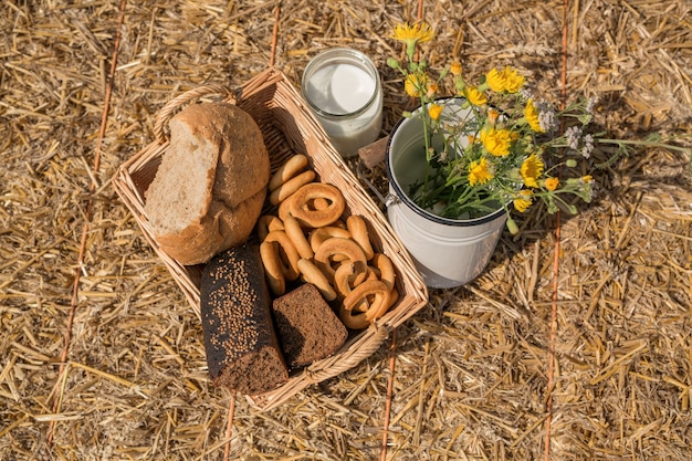 Una canasta de mimbre con pan para hacer un picnic en el campo y una lata de leche fresca.