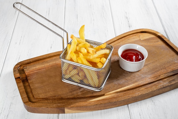 Canasta de papas fritas con salsa de tomate en el escritorio de madera