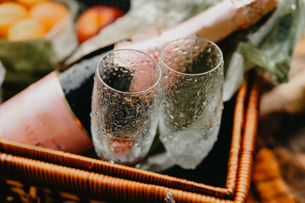 Canasta de picnic con una botella de champagne, fruta y una copa.